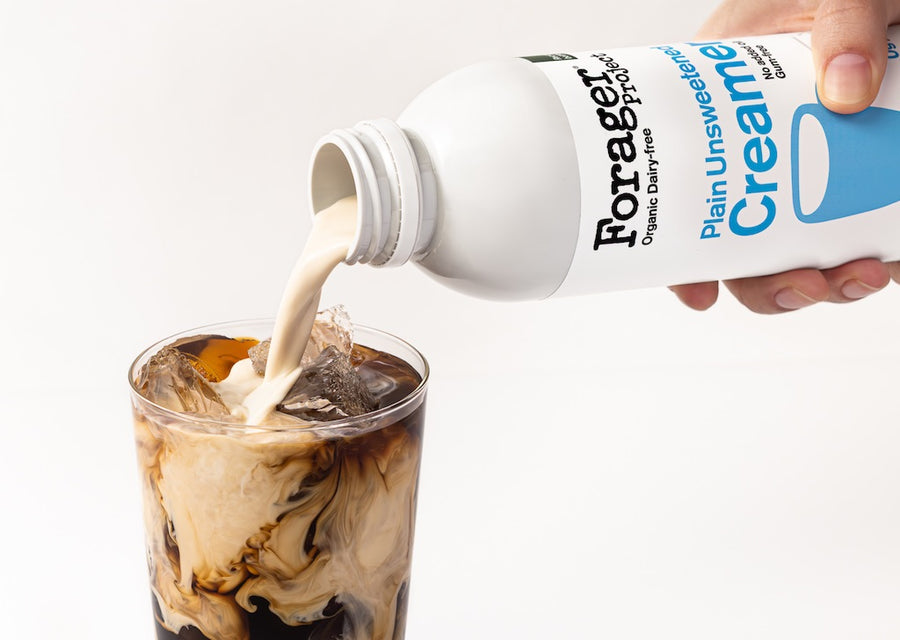 Forager Creamy Plain Unsweetened creamer being poured into a glass of iced coffee.