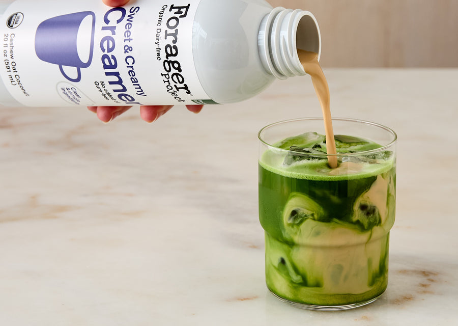 Forager Sweet & Creamy product being poured into a glass with a green drink.