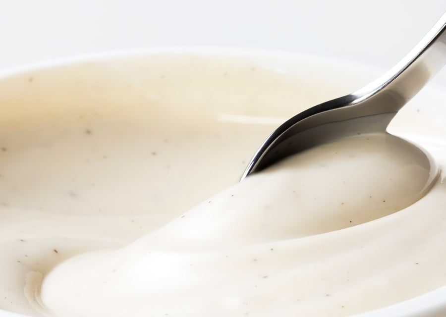 Close-up of a spoon dipping into creamy yogurt on a white background