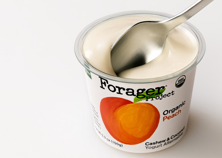 Forager Project Organic Peach Cashew & Coconut Yogurt Alternative with a spoon inside on a white background