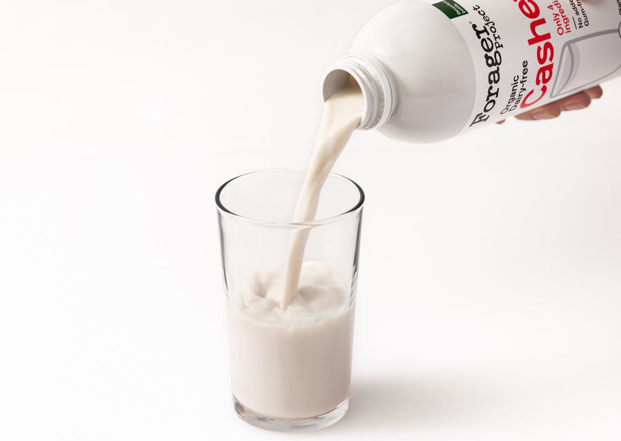 Organic Cashew Milk being poured into a glass on a white background