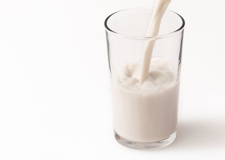 Glass of Cashewmilk being poured on a white background