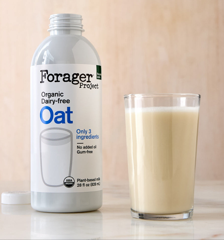 Forager Project oat milk bottle and glass on a wooden surface