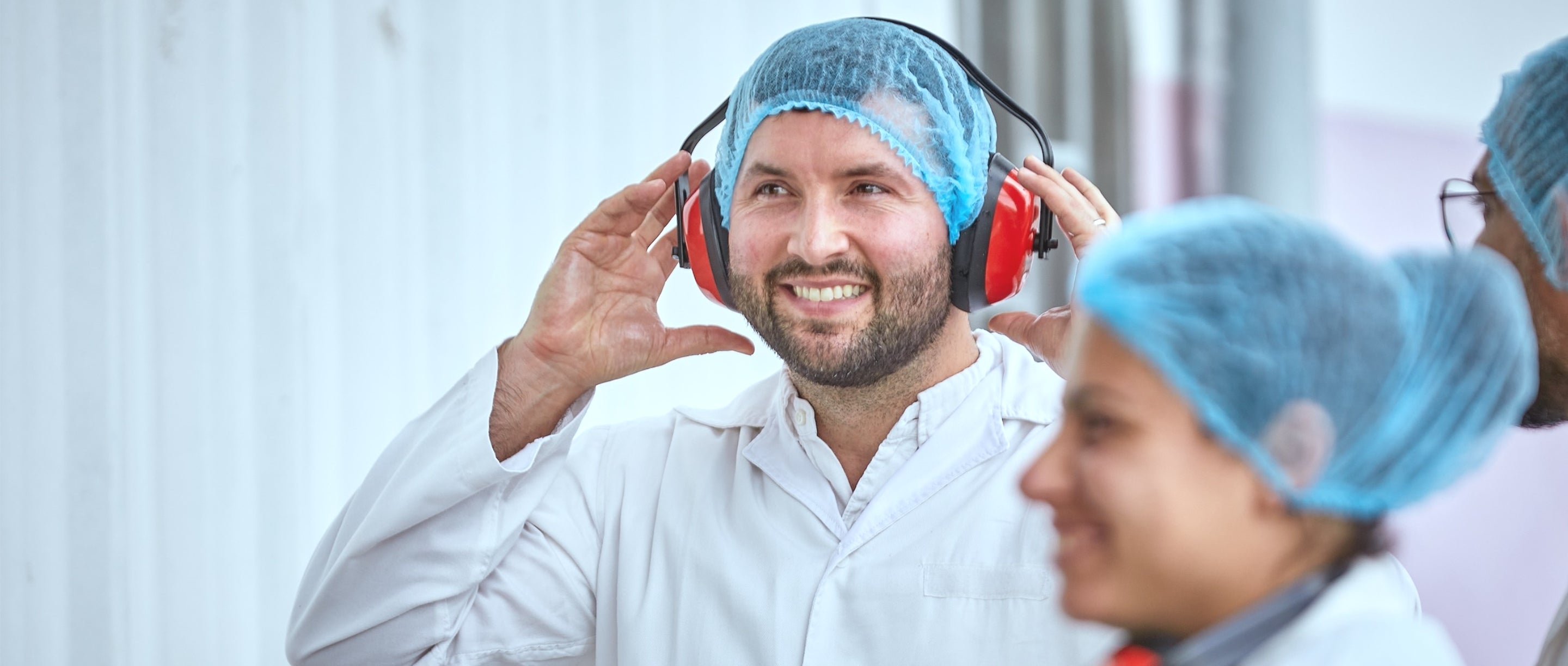 Person wearing ear protection with colleagues in a laboratory setting