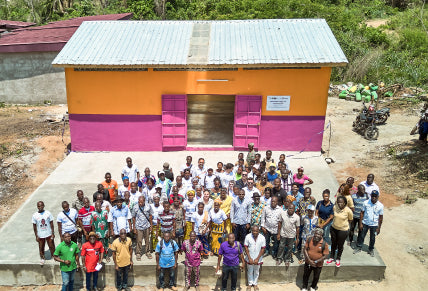 Group of people posing in front of a colorful building with an orange wall and pink doors.