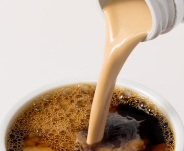 Cream being poured into a cup of coffee