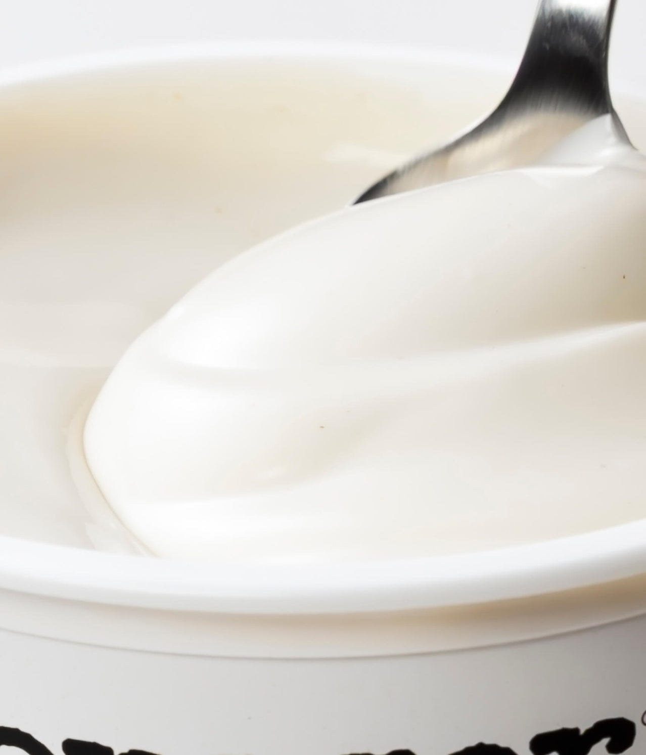 Close-up of a spoon dipping into a bowl of vanilla ice cream
