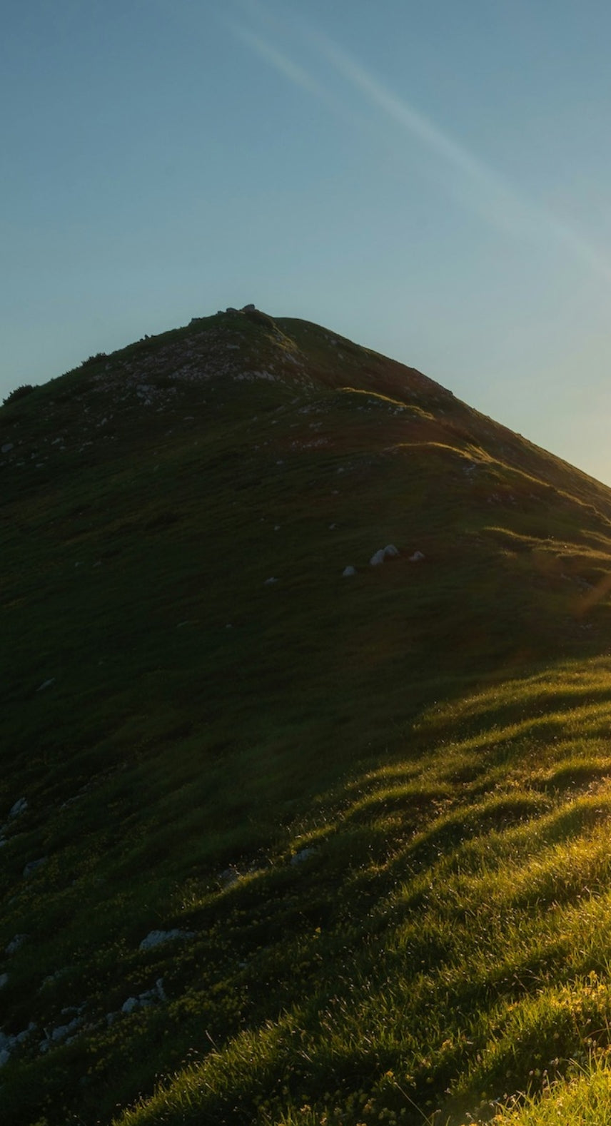 Sunrise over a mountain landscape with a path leading towards the sun.