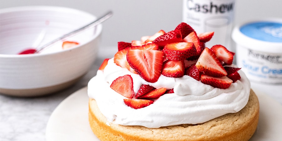 A strawberry shortcake next to a bowl and Forager Project Cashewmilk and sour cream containers.