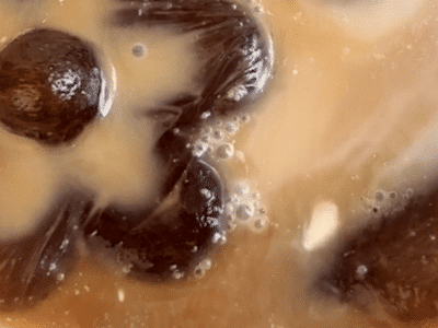 Extreme close up of a glass of dairy-free iced coffee with flower shaped ice cubes.