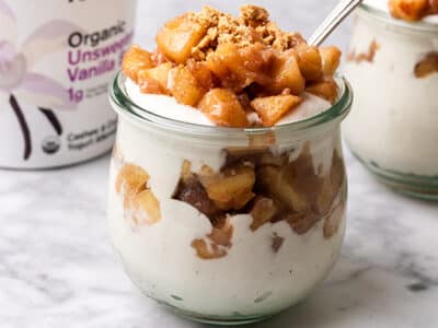 A couple of no bake apple cheesecake jars next to a tub of Unsweetened Vanilla Cashewmilk yogurt.