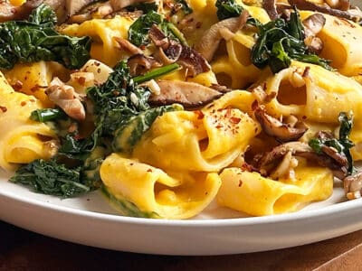 Close up of butternut squash pasta with sauteed kale and mushrooms