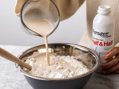 A person pouring Forager Project Dairy-Free Half & Half into a bowl.