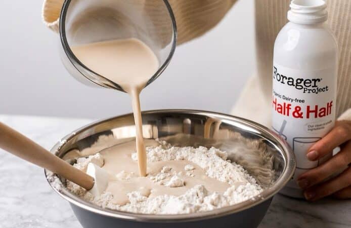 A person pouring Forager Project Dairy-Free Half & Half into a bowl.