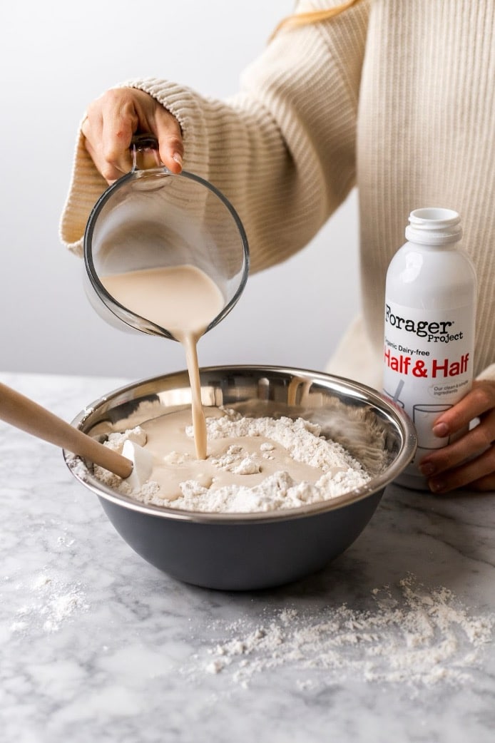 A person pouring Forager Project Dairy-Free Half & Half into a bowl.