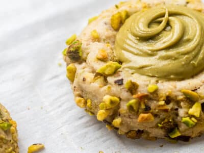 White baking sheet with pistachio Thumbprint cookies topped with a creamy pistachio filling.